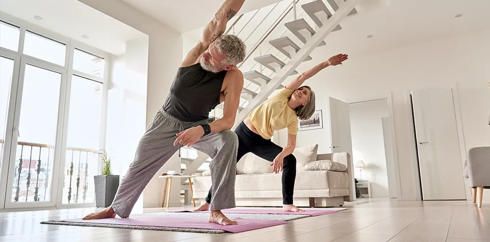 Older couple doing a side lunge stretch at home