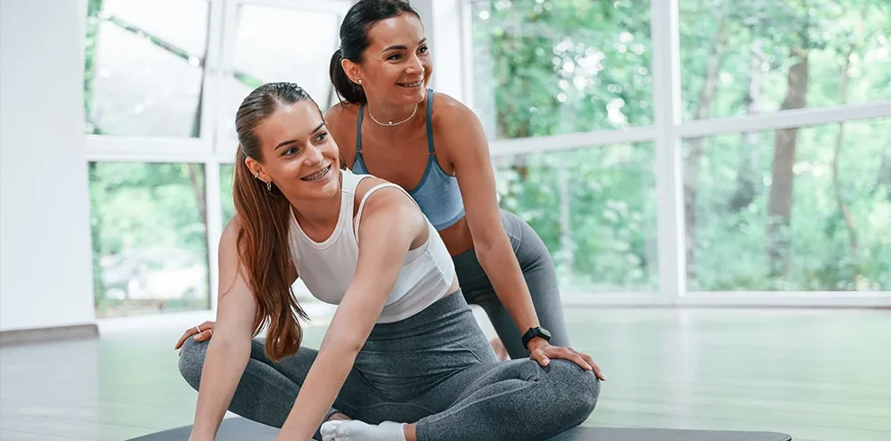 Personal trainer and client stretching together